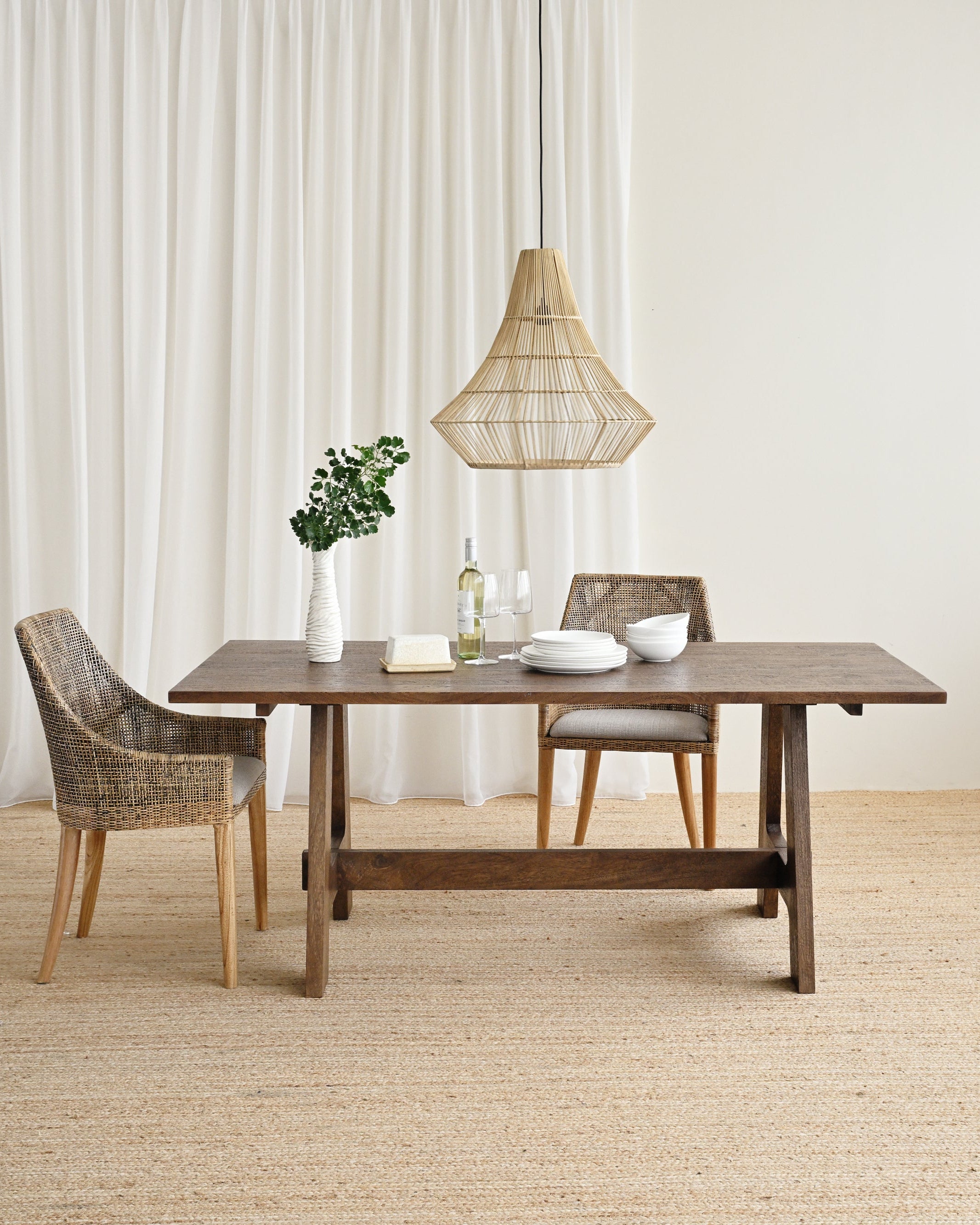 Dining area with a wooden table and chairs in a room with white curtains.