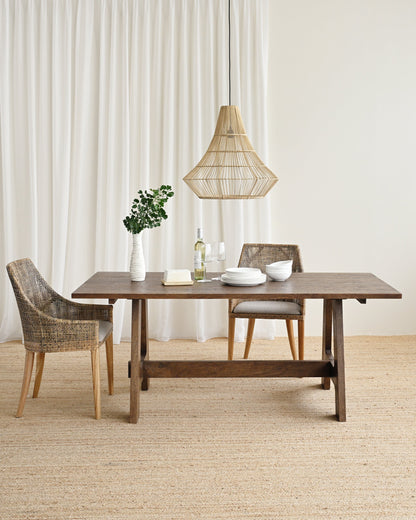 Dining area with a wooden table and chairs in a room with white curtains.
