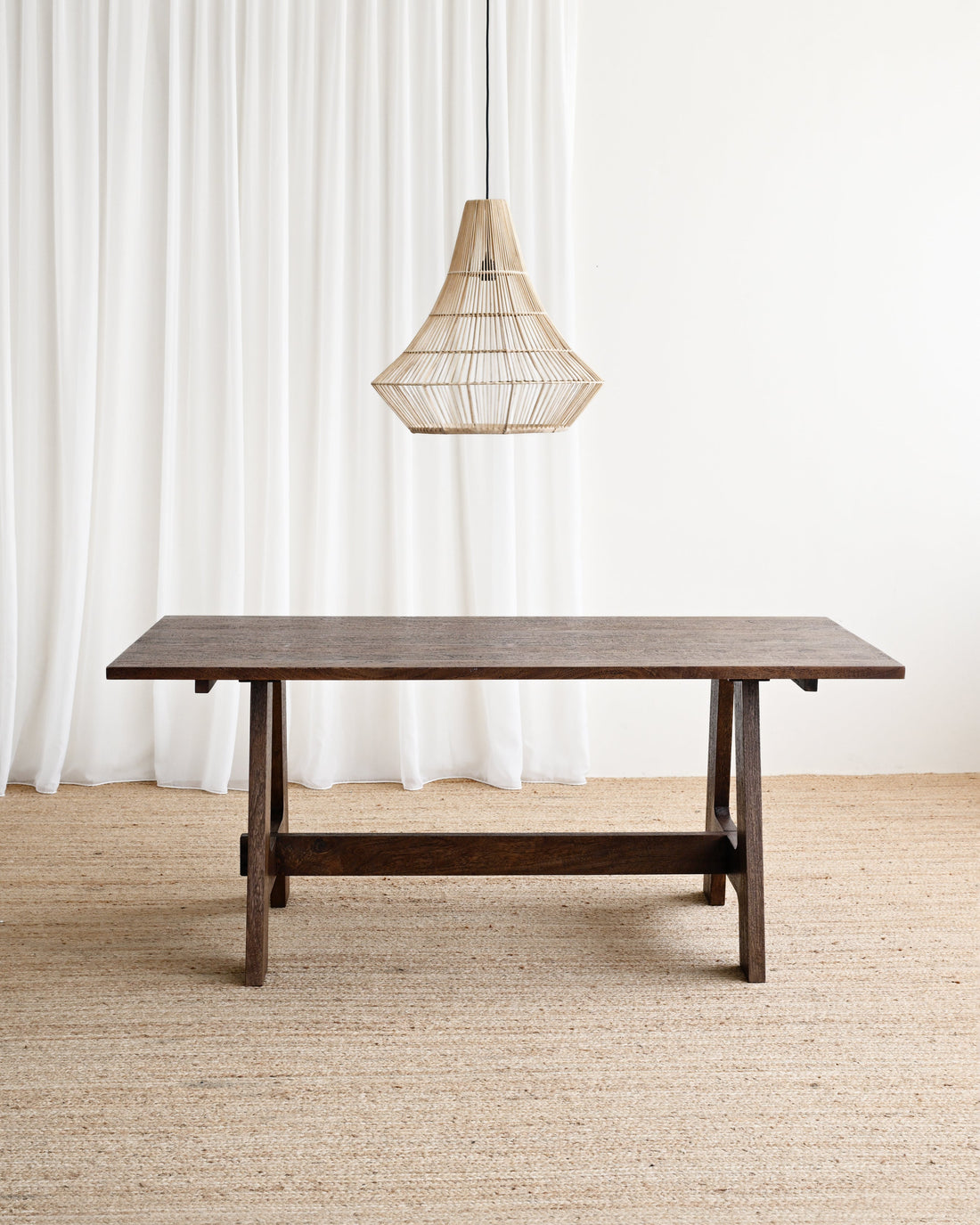 Wooden table with a hanging lamp against a white curtain background