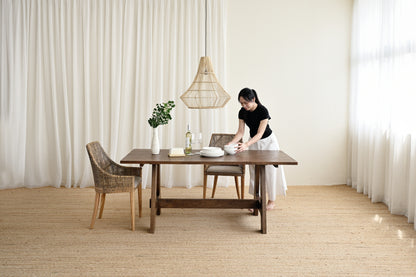 Woman setting a table in a room with large windows and neutral decor