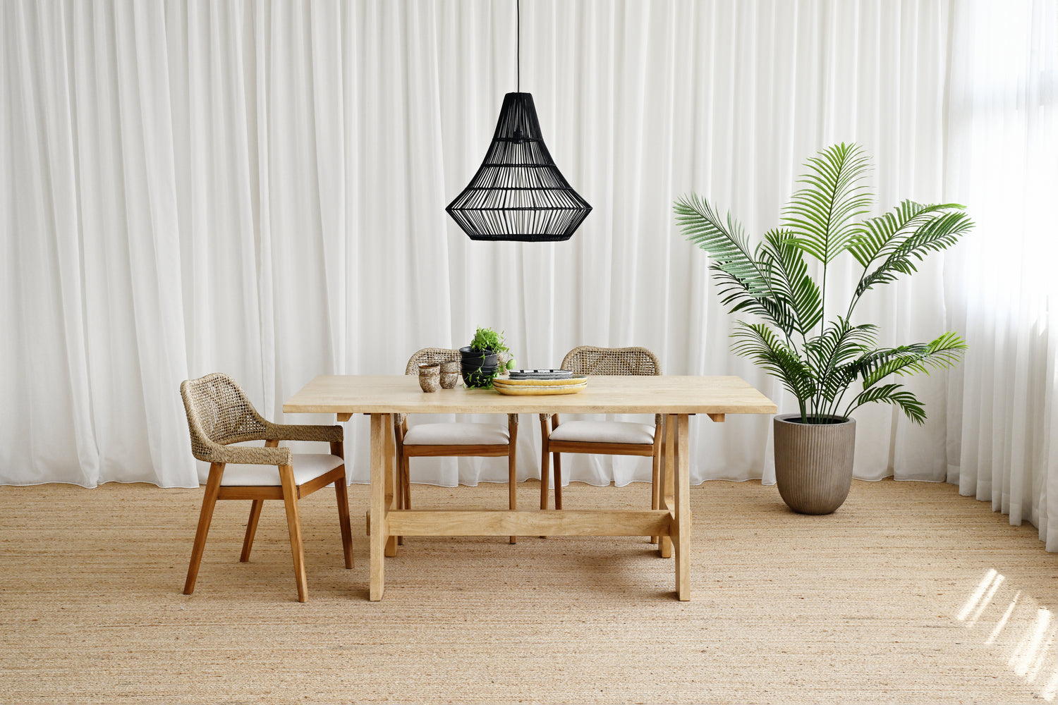 Dining area with wooden table and chairs, black pendant light, and potted plant.