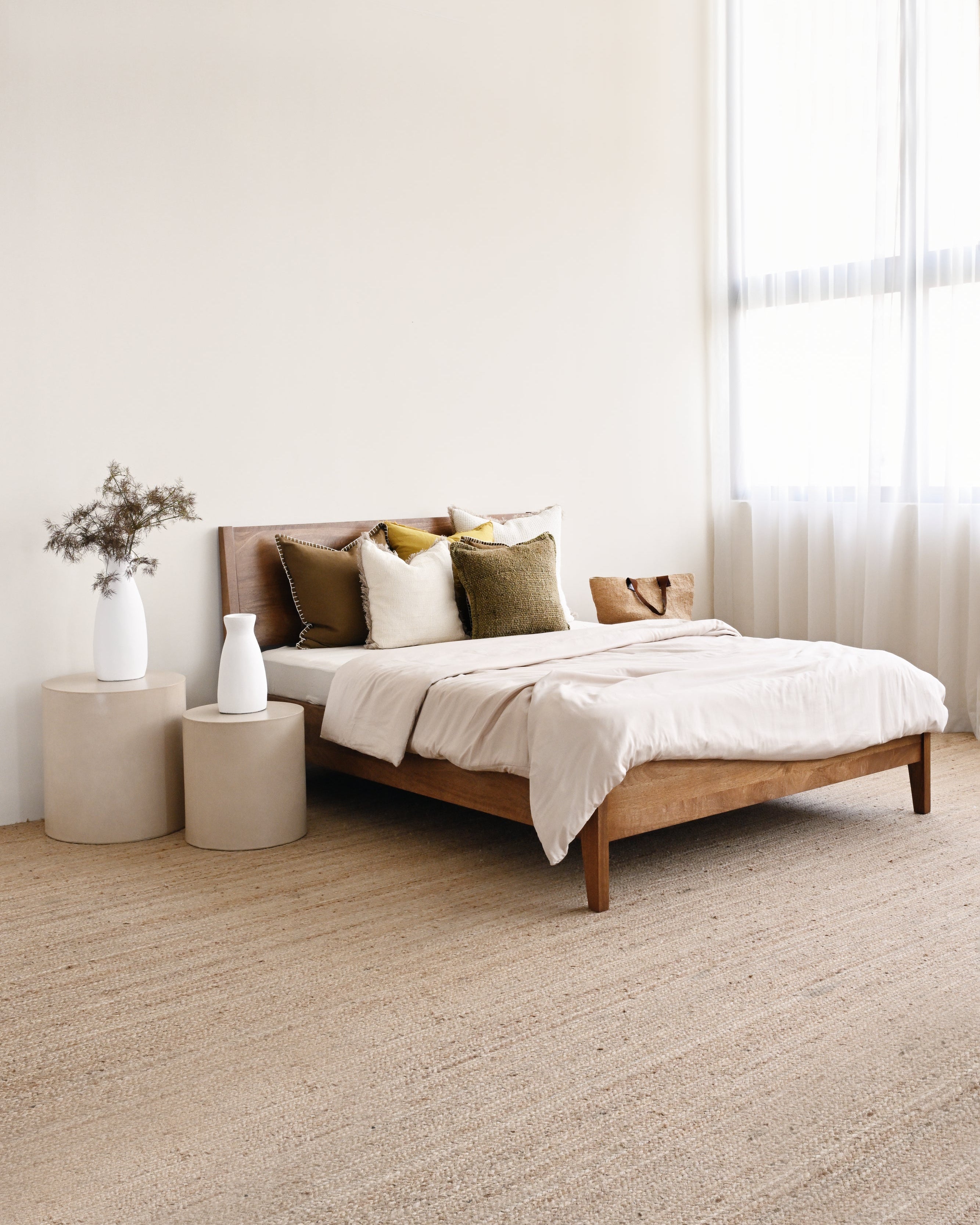 Bedroom with a wooden bed, beige bedding, and side tables.
