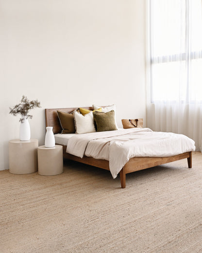 Bedroom with a wooden bed, beige bedding, and side tables.