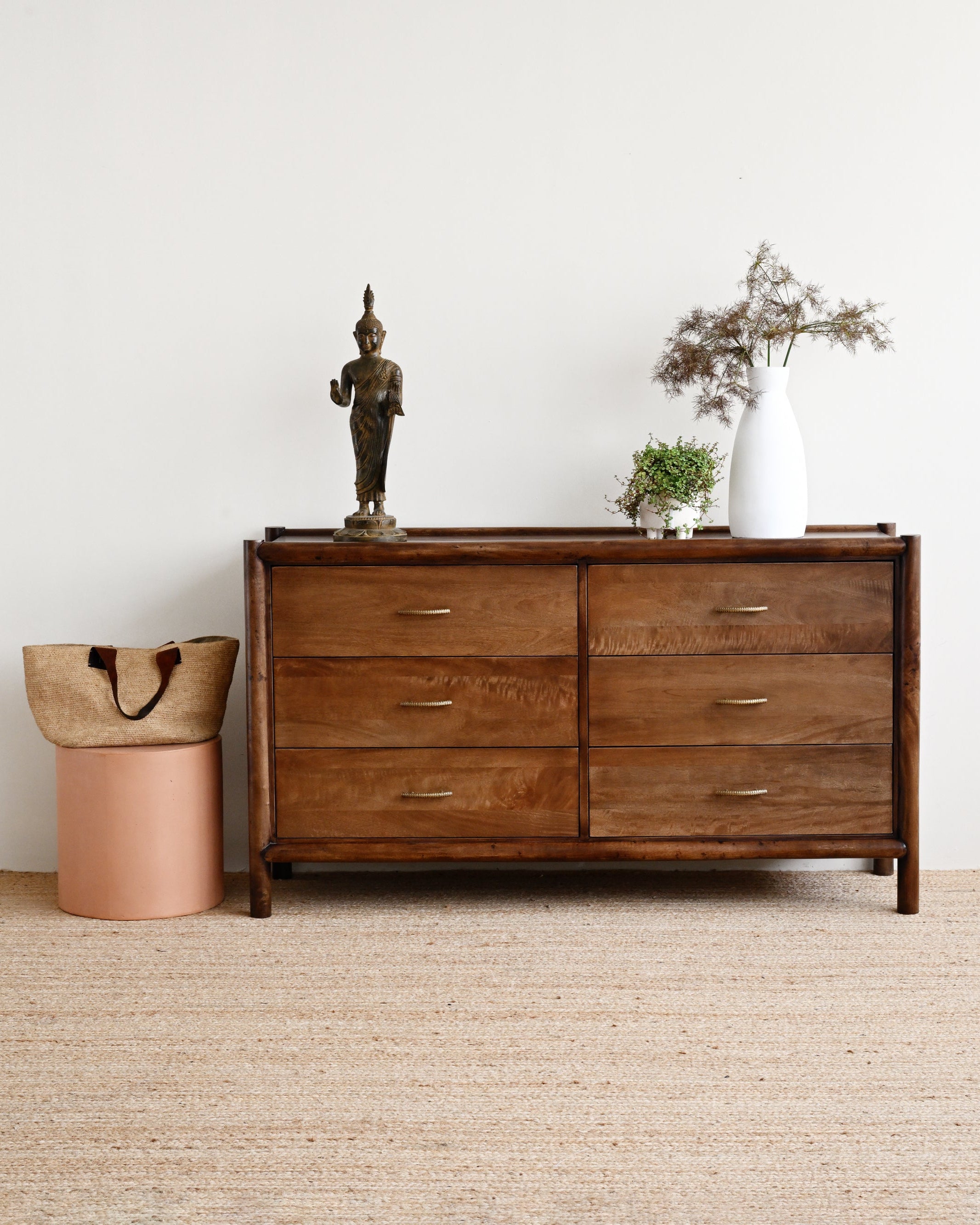 Wooden dresser with decorative items against a white wall