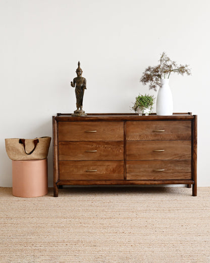 Wooden dresser with decorative items against a white wall