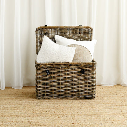 Wicker basket with white pillows against a white curtain background