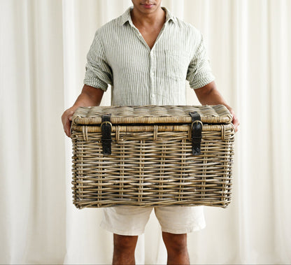 Man holding a wicker basket against a white curtain background