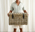 Man holding a wicker basket against a white curtain background