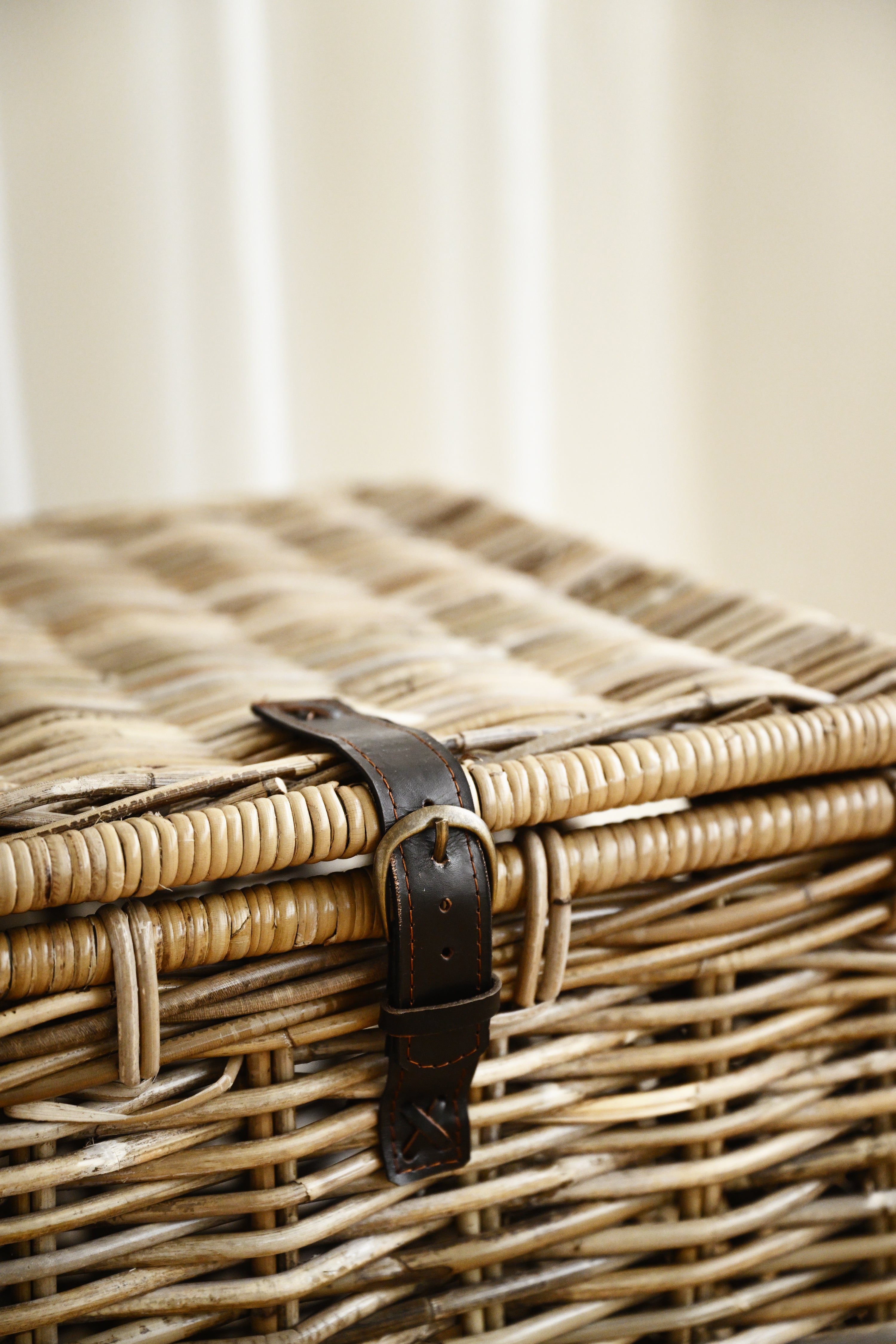 Wicker basket with a leather handle on a neutral background