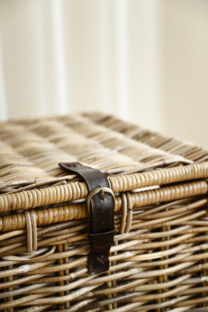 Wicker basket with a leather handle on a neutral background