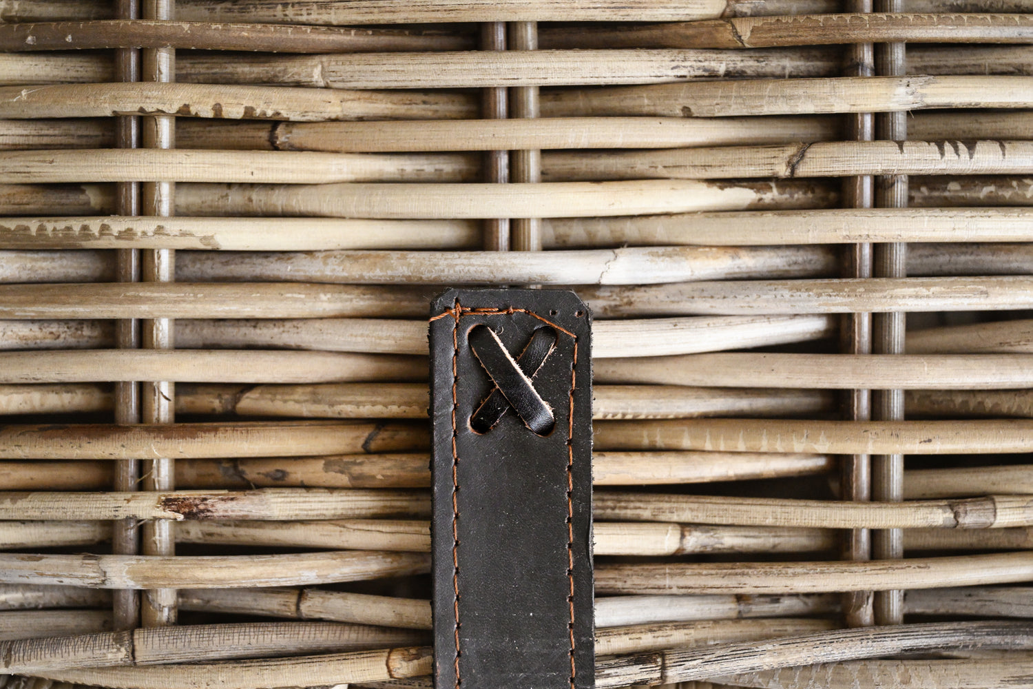 Close-up of a woven basket with a leather tag featuring a metal clasp.