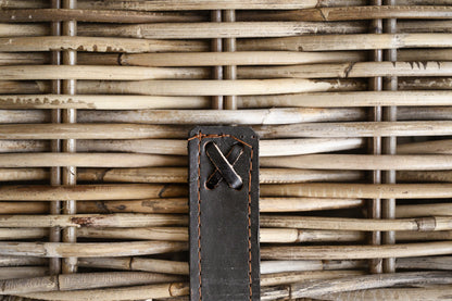 Close-up of a woven basket with a leather tag featuring a metal clasp.