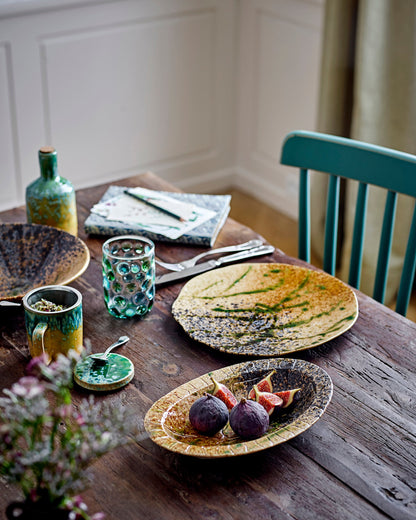 Dining table with ceramic plates, glasses, and cutlery in a home setting.