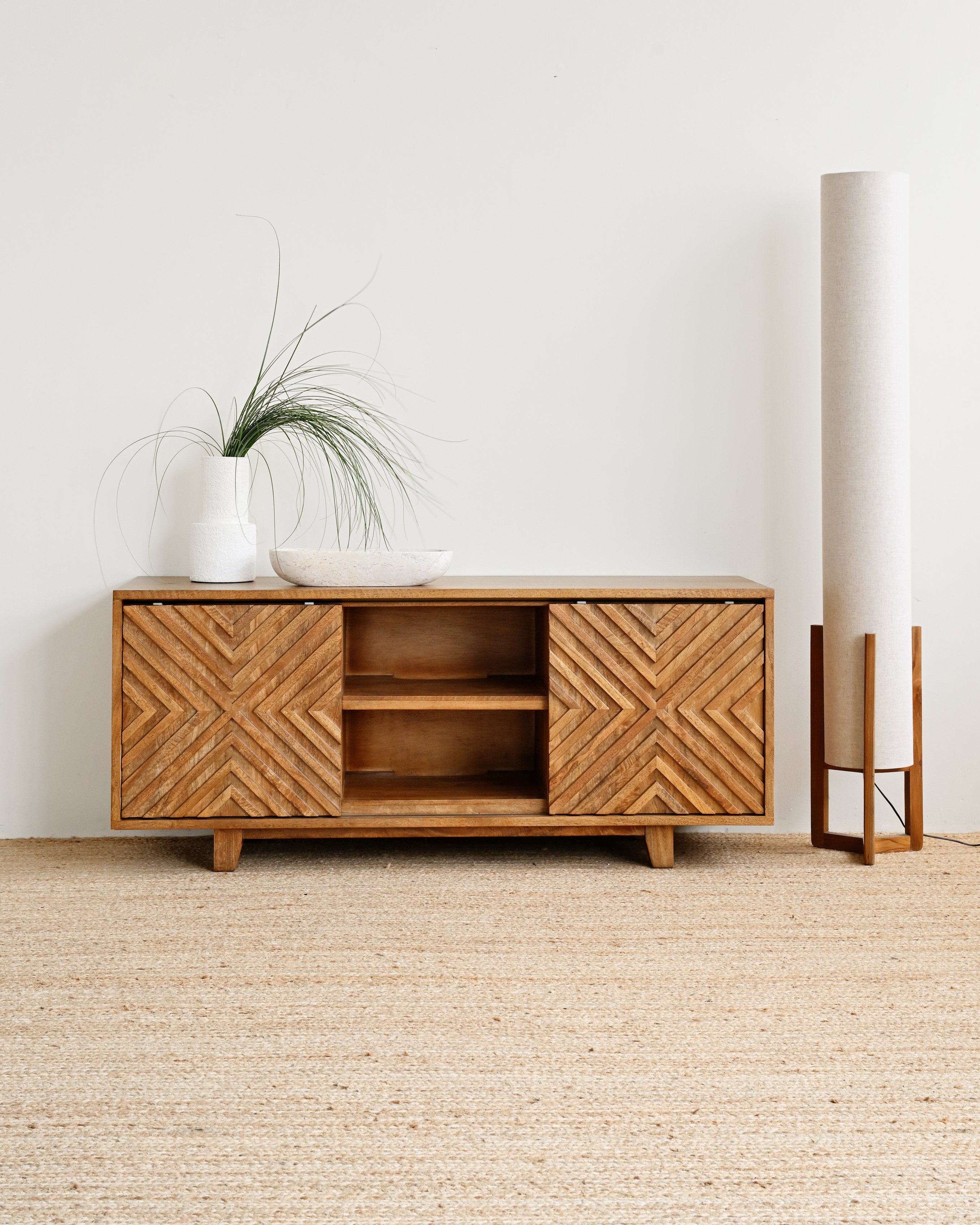 Wooden cabinet with decorative patterns in a minimalistic room.