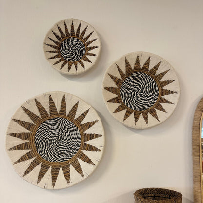 A set of three wall deco items made of natural and white fibers with a geometric pattern, handmade in Indonesia, displayed on a wall.