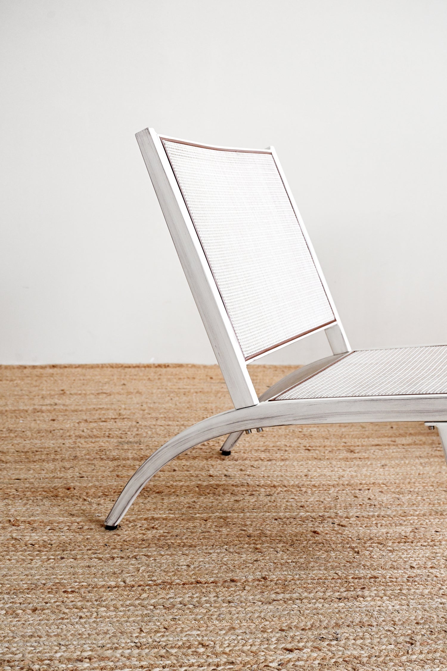White chair on a textured brown floor with a white wall background