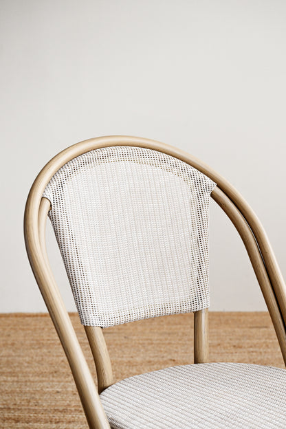 Chair with woven backrest and seat on a neutral background