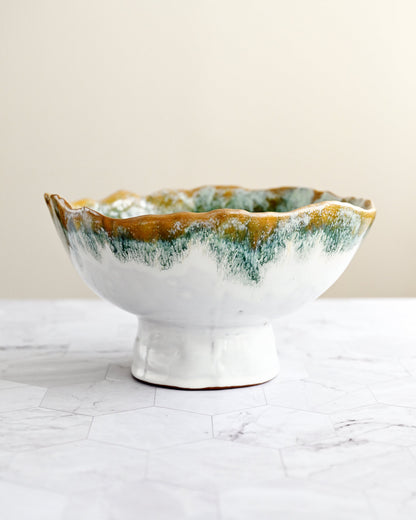 Ceramic bowl with green and brown glaze on a white surface