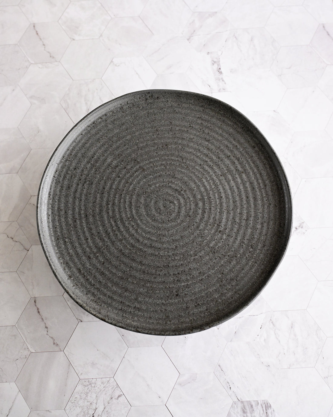 Black textured plate on a light marble surface