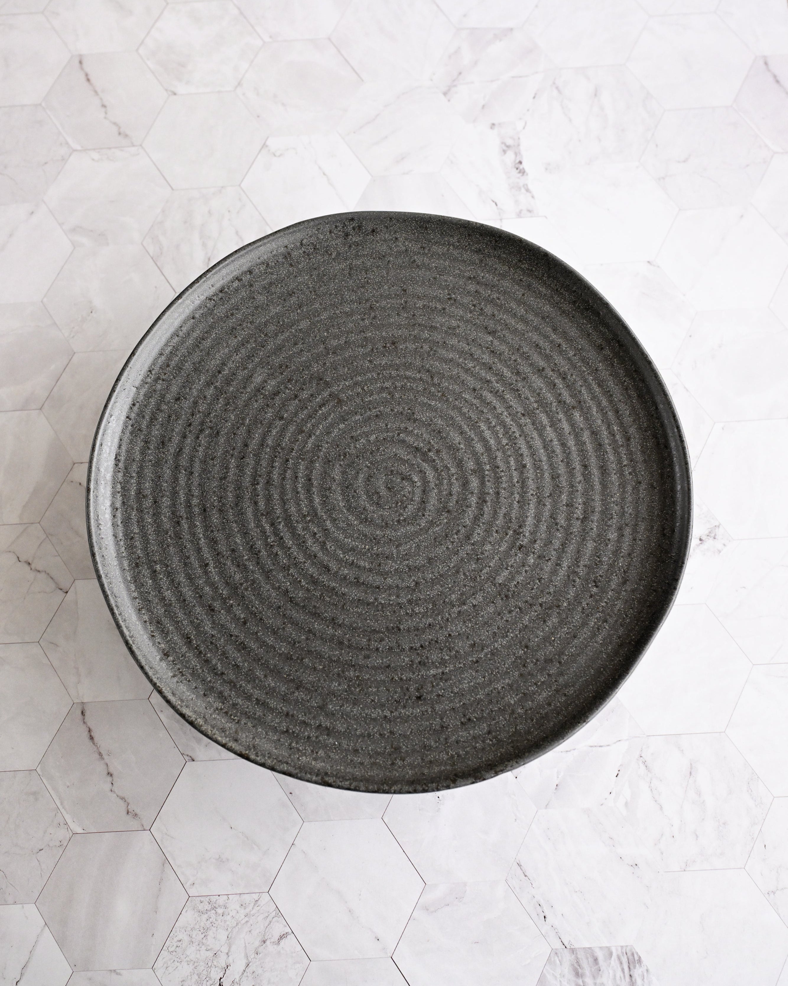 Black textured plate on a light marble surface