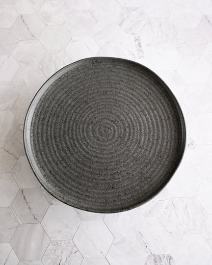 Black textured plate on a light marble surface