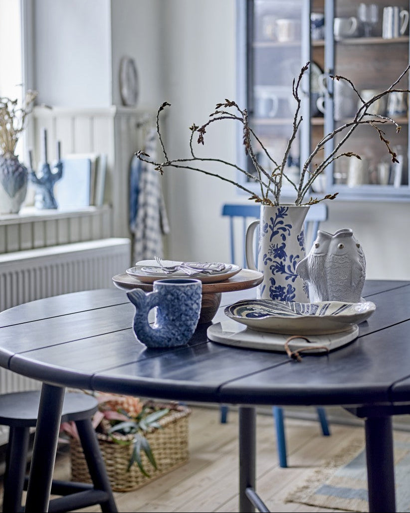 Dining room with a table set with blue and white ceramic items, including a pitcher and mugs.
